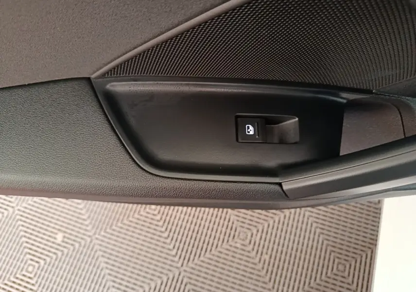 Bouton de verrouillage des portes sur la portière intérieure noire d'une Audi A3 blanche, vue en gros plan.