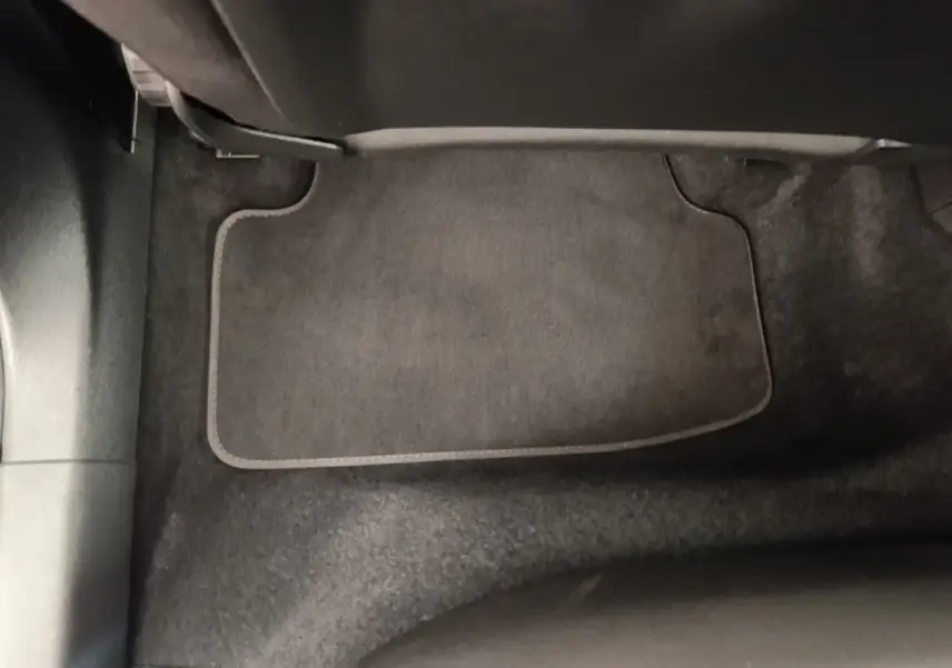 Vue rapprochée du tapis de sol noir côté passager avant de l'Audi A3 40 TFSI e blanc, intérieur sobre et propre.
