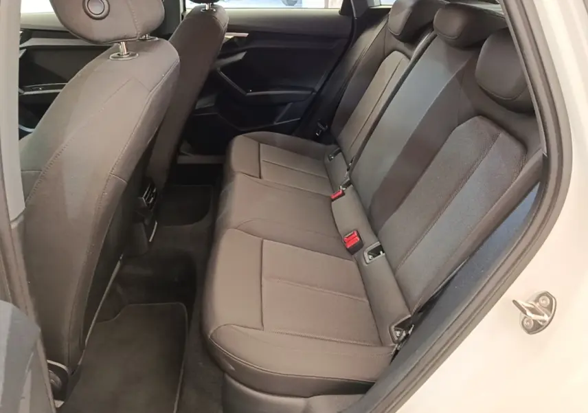 Vue intérieure côté droit sur la banquette arrière grise de l'Audi A3 40 TFSI e blanche, avec porte ouverte.
