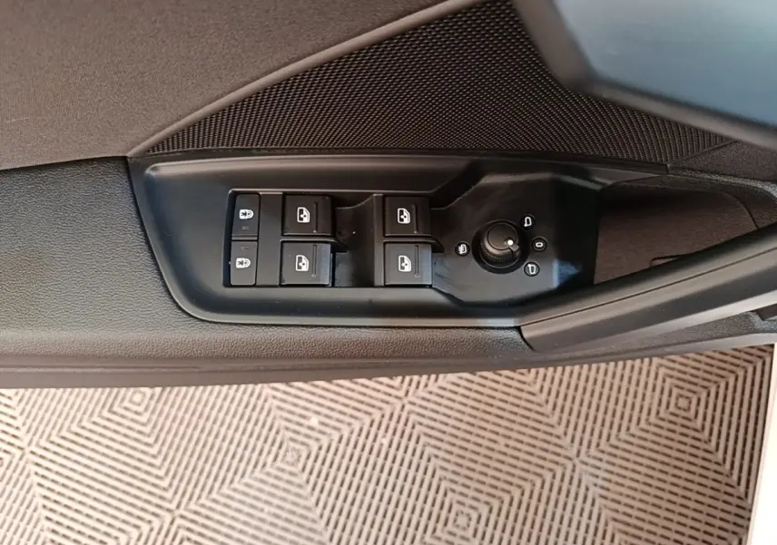 Gros plan sur les commandes de lève-vitres et réglage des rétroviseurs côté conducteur d'une Audi A3 blanche.