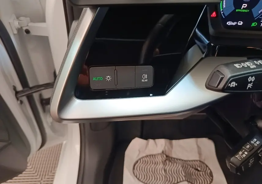 Vue intérieure côté gauche du tableau de bord de l'Audi A3 blanc, avec commandes d’éclairage et levier multifonctions visibles.