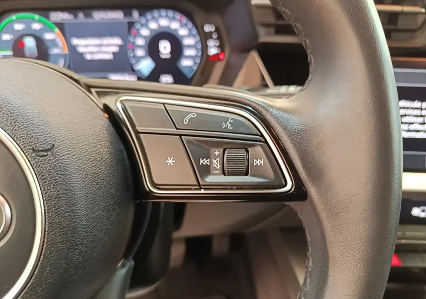 Gros plan sur le volant cuir noir de l'Audi A3 40 TFSI e 2022 avec commandes multimédia intégrées à droite.