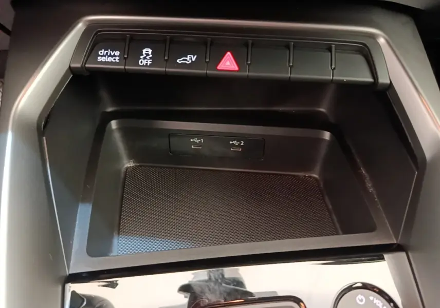 Gros plan sur la console centrale noire de l’Audi A3 40 TFSI e 2022, avec boutons de contrôle et ports USB visibles.