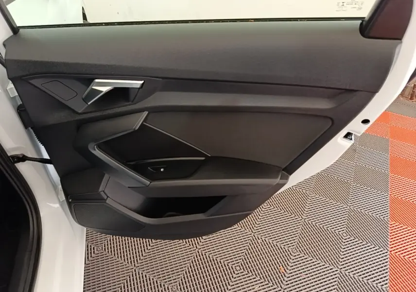 Vue rapprochée de la porte avant gauche blanche d’une Audi A3 40 TFSI e 2022 avec garniture intérieure noire.