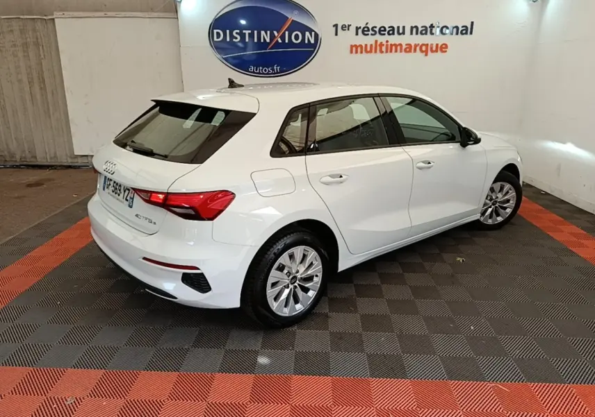 Audi A3 40 TFSI e blanche vue 3/4 arrière droit dans un showroom avec logo Distinxion en arrière-plan.