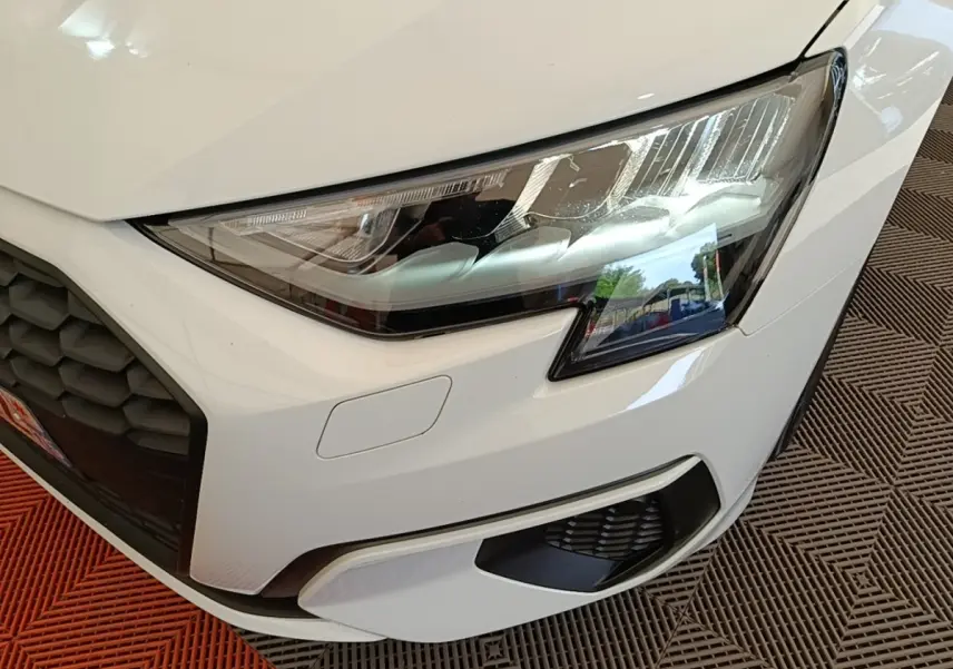 Gros plan sur l'avant droit blanc d'une Audi A3 40 TFSI e 2022, mettant en valeur le phare LED et la calandre noire.