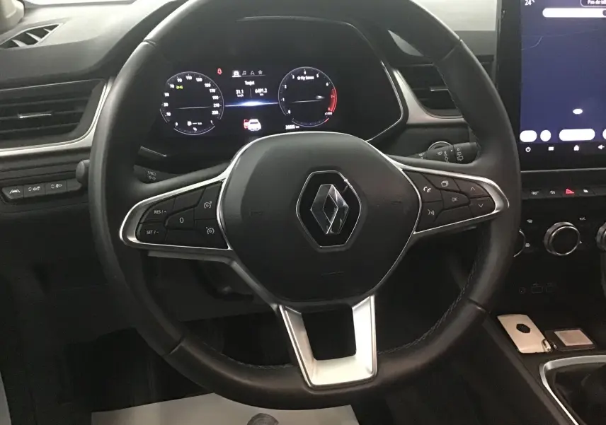 Vue centrée sur le volant noir du Renault Captur 2024 avec tableau de bord numérique et écran tactile latéral.