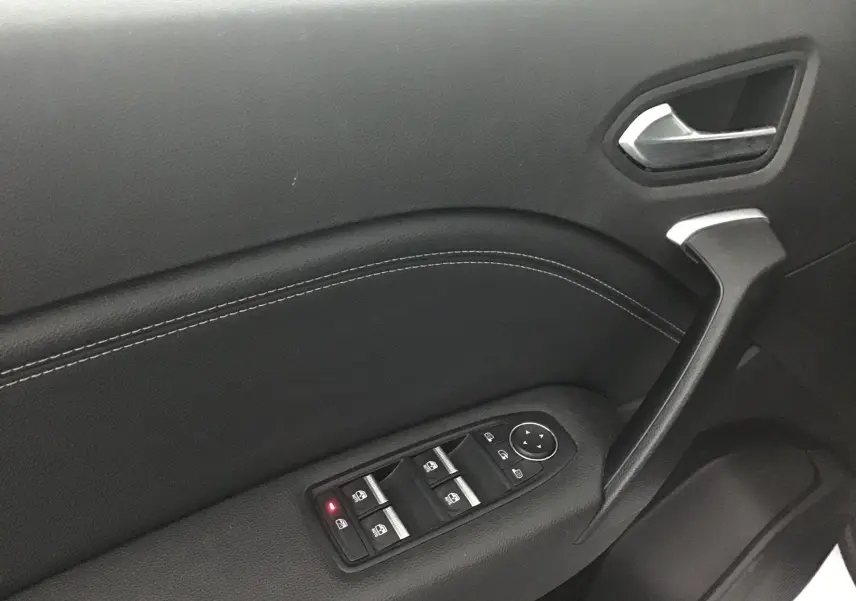 Gros plan sur la porte côté gauche du Renault Captur blanc nacré, mettant en valeur les commandes électriques des vitres et la poignée noire.