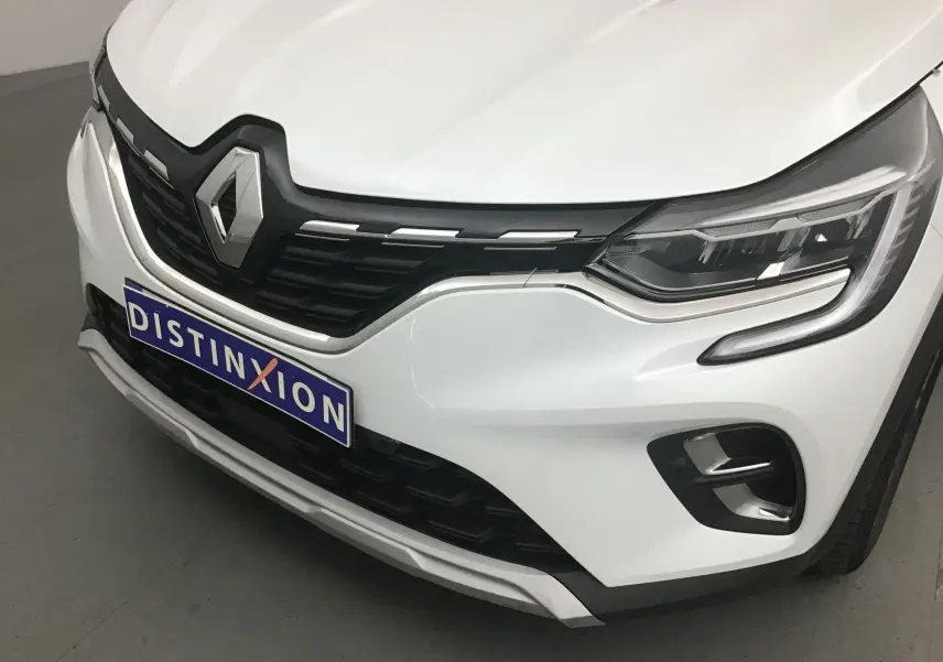 Gros plan sur l'avant droit du Renault Captur blanc nacré avec calandre noire et feux LED distinctifs.