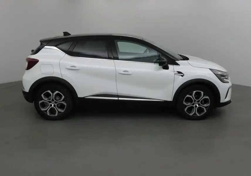 Profil côté gauche du Renault Captur 2024 blanc nacré avec toit noir et détails noirs contrastants.