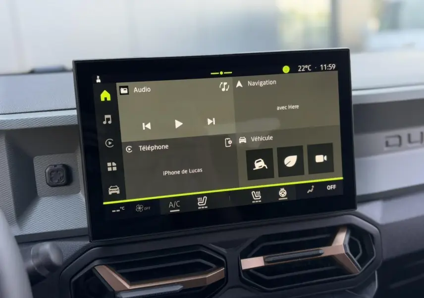 Écran tactile 10 pouces du tableau de bord du Dacia Duster 2025, avec commandes climatisation et finition brun cuivré.