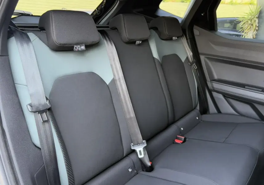 Banquette arrière en tissu bicolore gris et noir du Dacia Duster 2025 vue côté droit, avec ceintures de sécurité visibles.