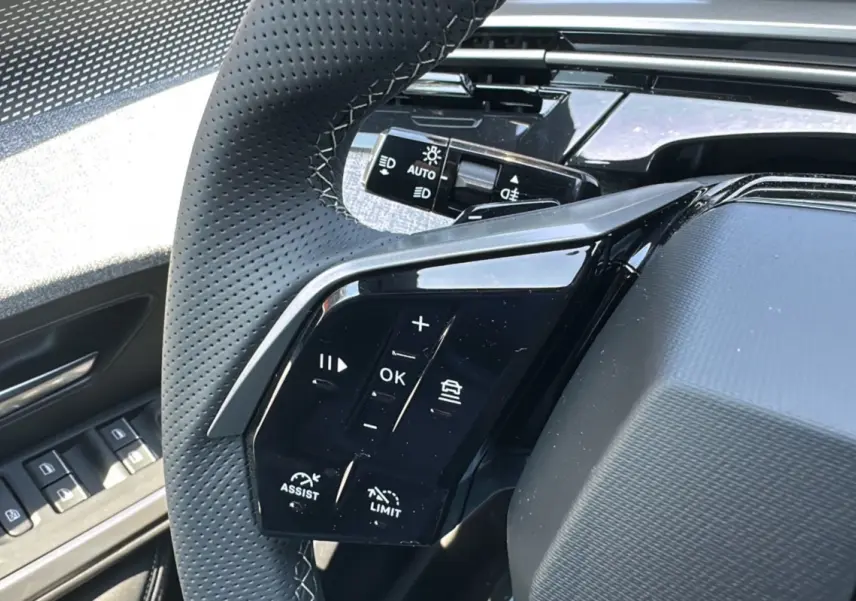 Gros plan sur le volant perforé du Peugeot 3008 Hybrid 145 GT Alcantara 2025 avec commandes multifonctions à gauche.