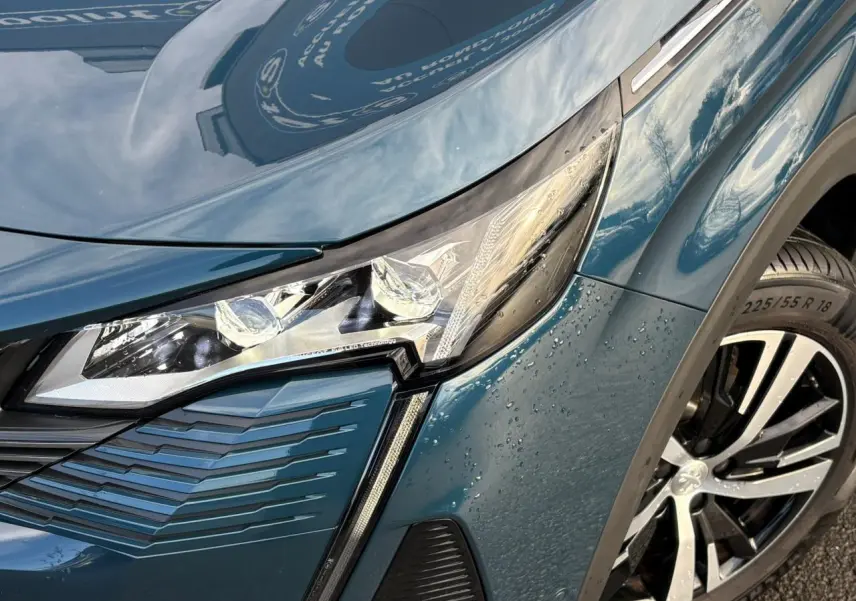 Gros plan sur l'avant droit du Peugeot 3008 bleu Célèbes, mettant en valeur le phare LED et la jante alliage 18 pouces.
