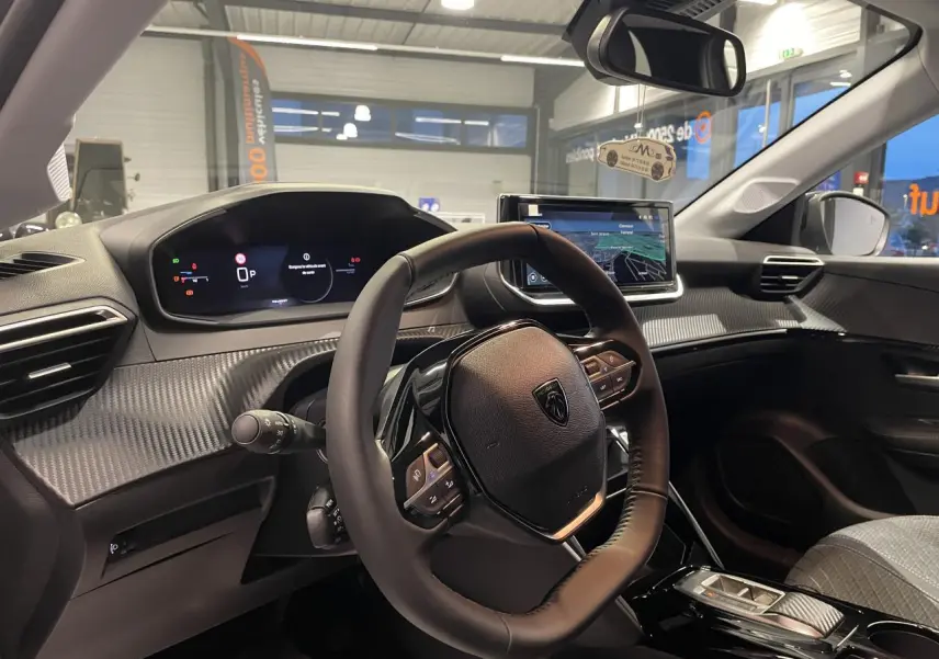 Vue intérieure côté conducteur du Peugeot 208 1.2i Hybrid 2025 avec tableau de bord numérique et volant cuir noir.