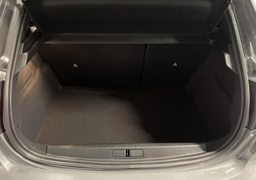 Coffre ouvert vu de l'arrière d'une Peugeot 208 gris selenium, montrant l'espace de chargement vide.