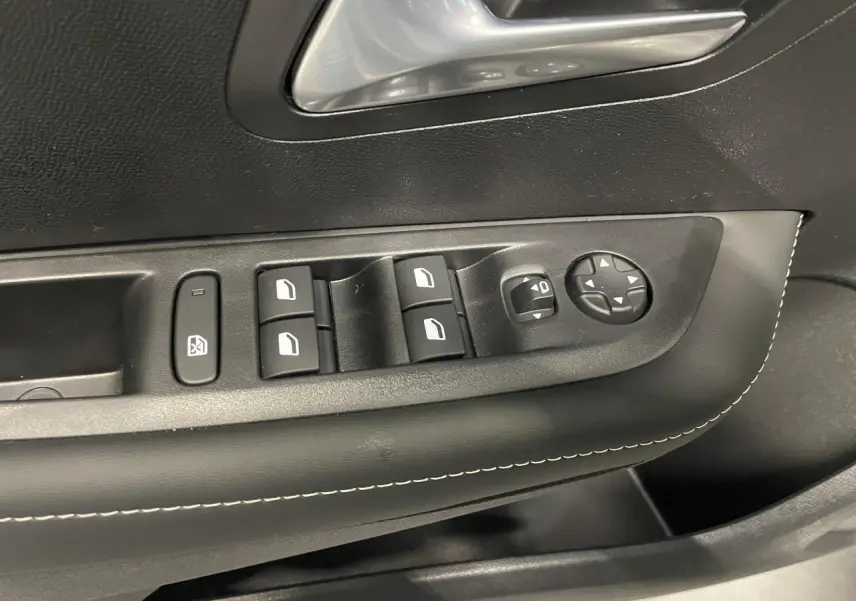 Détail des commandes de lève-vitres et rétroviseurs sur la porte avant gauche d’une Peugeot 208 gris selenium.