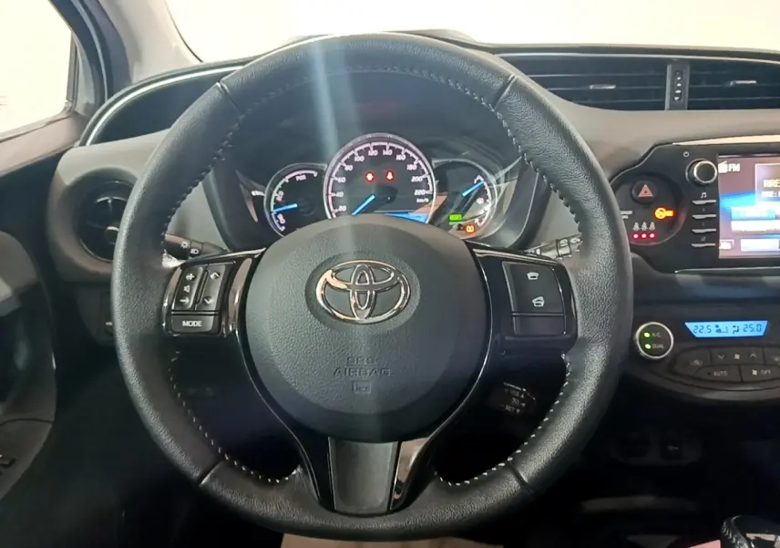 Vue intérieure centrée sur le volant cuir noir de la Toyota Yaris hybride 2019 avec tableau de bord et écran tactile.