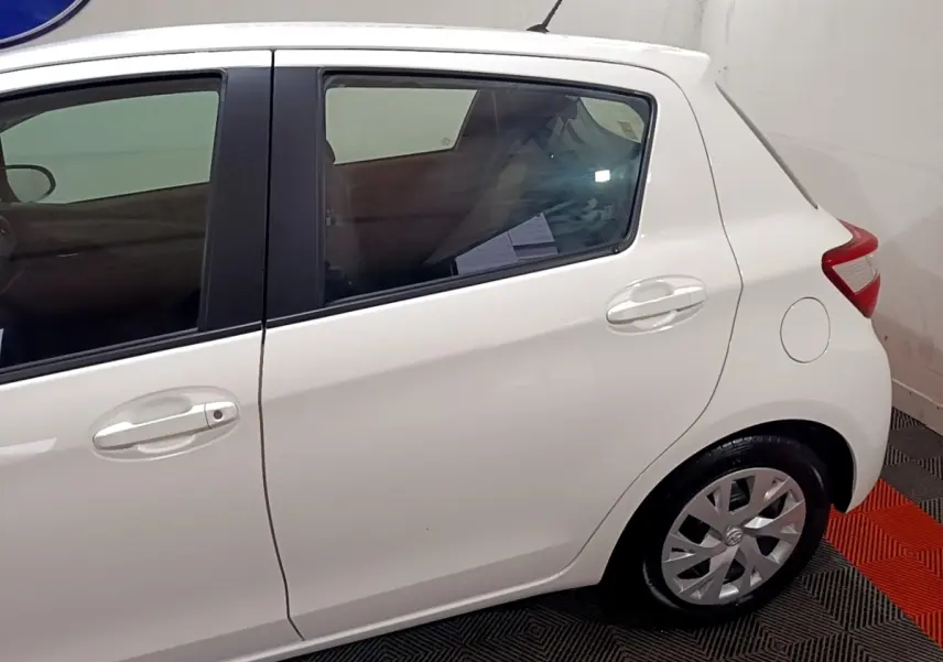Vue latérale droite d'une Toyota Yaris blanche 2019, mettant en valeur les poignées de porte et la roue arrière.
