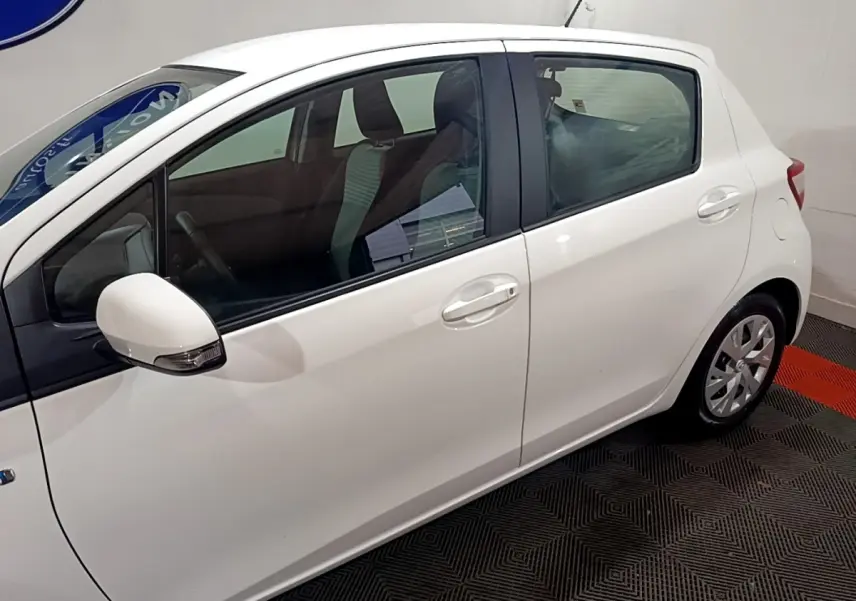 Vue de profil côté gauche d'une Toyota Yaris blanche 5 portes, avec rétroviseur blanc et jantes compactes.