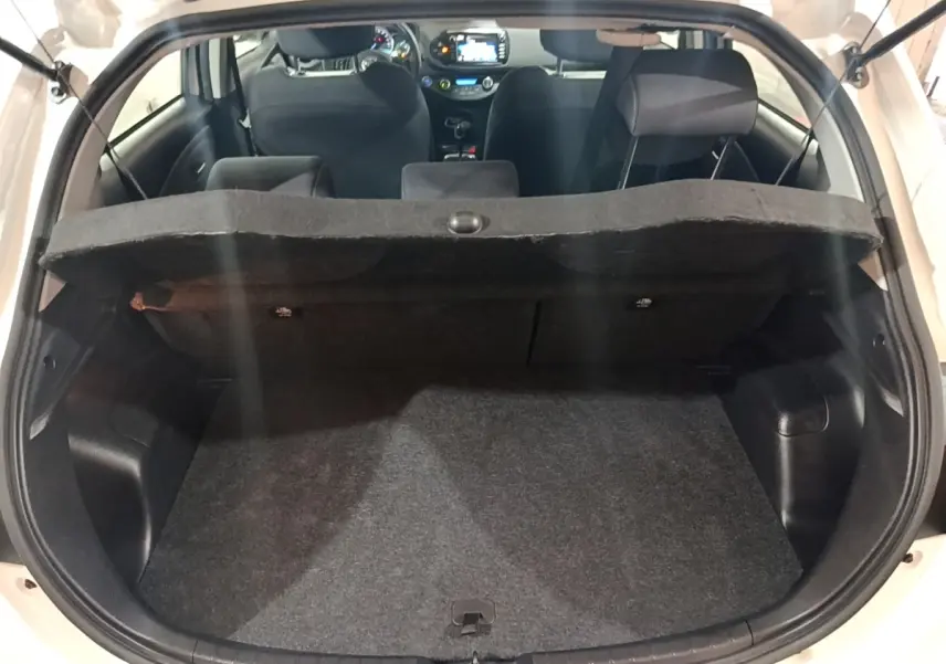 Coffre ouvert d’une Toyota Yaris blanche vue de l’arrière, montrant l’habitacle et la tablette de coffre relevée.