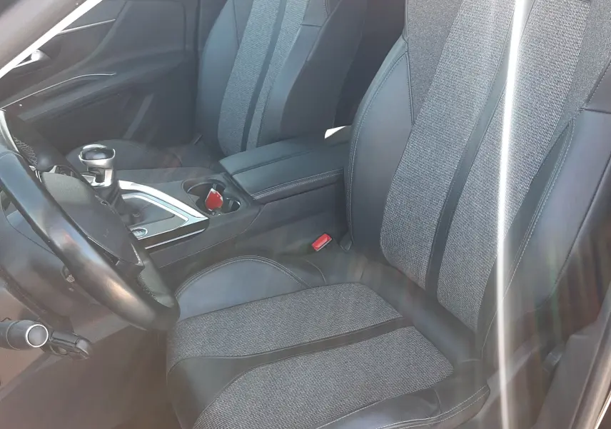 Vue intérieure côté conducteur du Peugeot 3008 noir, sièges bi-matière tissu et cuir avec console centrale et levier de vitesse manuelle.