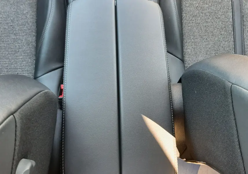 Vue plongeante sur l'accoudoir central noir et les sièges tissu gris du Peugeot 3008 1.2 PureTech 130ch Allure.