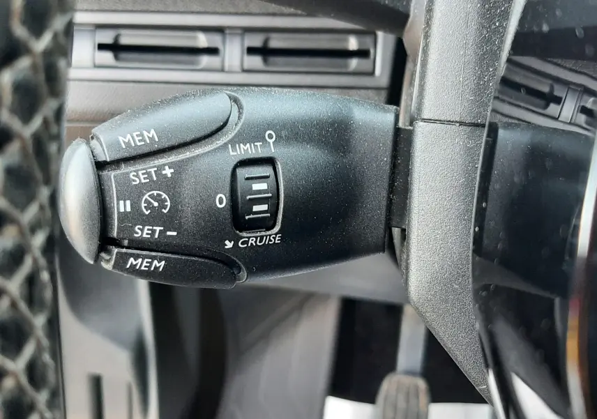 Gros plan sur la commande de régulateur de vitesse noire à gauche du volant du Peugeot 3008 noir de 2019.