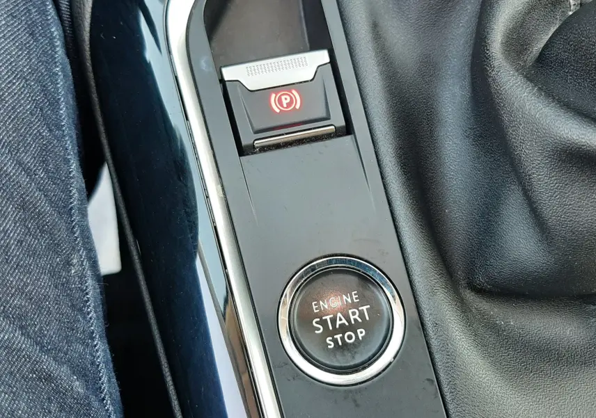 Gros plan sur la console centrale noire du Peugeot 3008 2019, montrant le bouton Start/Stop et le frein à main électronique.