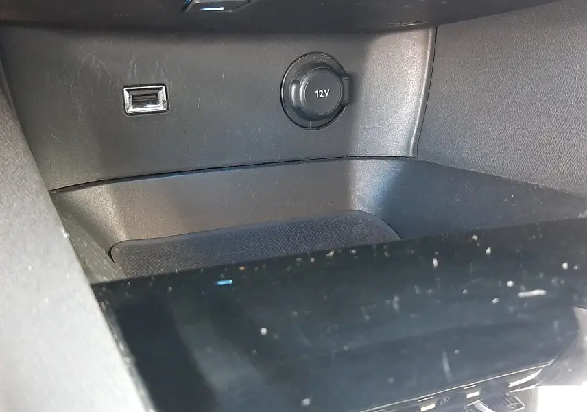 Prise 12V et port USB en gros plan dans l'habitacle noir du Peugeot 3008 2019, version essence manuelle.