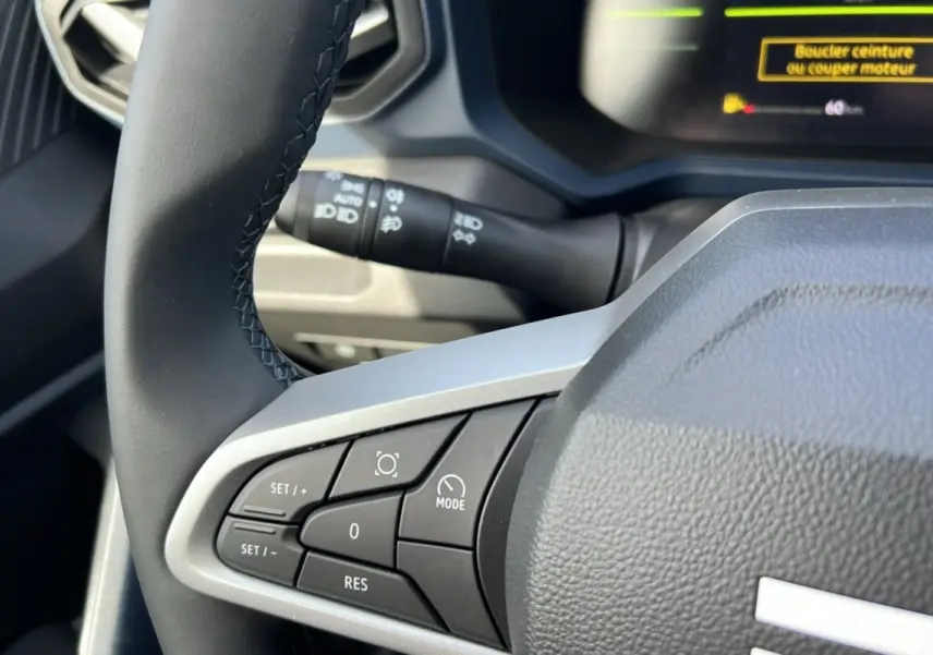 Gros plan sur le volant noir du Dacia Bigster Hybrid 155 Expression Plus avec commandes intégrées côté gauche.