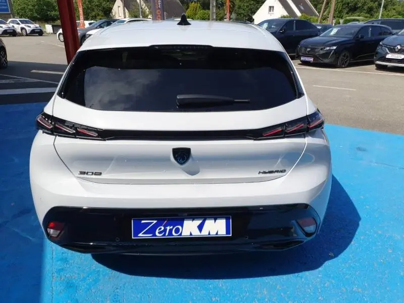 Vue arrière d'une Peugeot 308 Hybrid blanche Okénite avec feux arrière LED et lunette arrière surteintée.