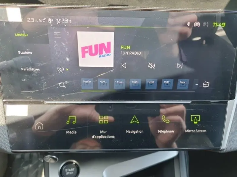 Écran tactile central du Peugeot 308 blanc Okénite, affichant la radio FUN et les options multimédia, vue de face.