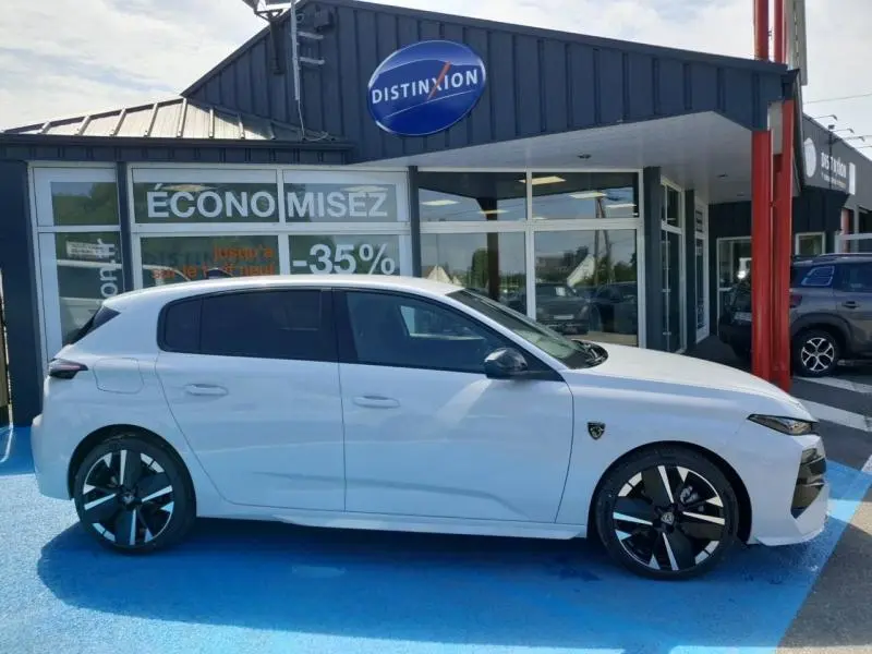 Peugeot 308 Hybrid blanc Okénite vue de profil côté gauche, jantes alu noires et logo GT visible sur la porte avant.