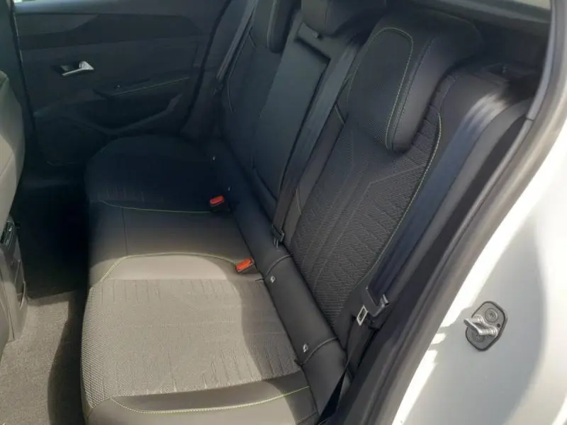 Vue intérieure côté droit des sièges arrière en tissu noir avec surpiqûres vertes d'une Peugeot 308 blanche.