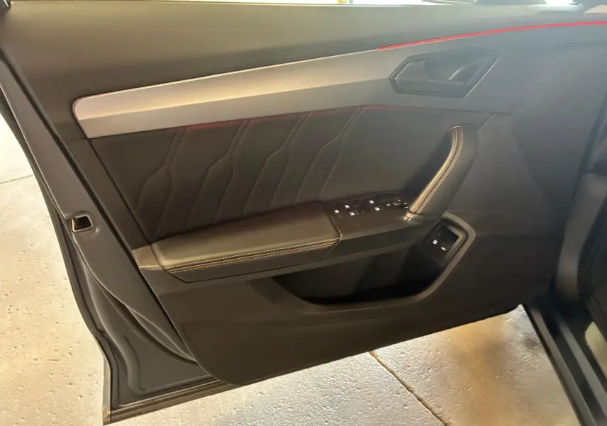 Vue intérieure côté gauche de la porte avant d'une CUPRA Formentor 1.4 E-HYBRID 2024 avec garniture noire et surpiqûres contrastantes.
