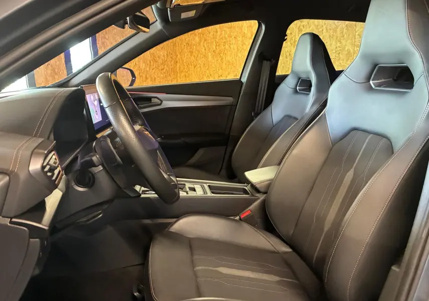 Intérieur avant de la CUPRA Formentor 1.4 E-HYBRID 2024, vue côté conducteur, sièges sport noirs avec surpiqûres contrastées.
