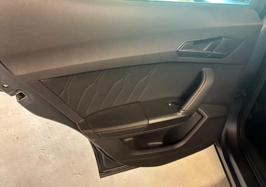 Vue rapprochée de la porte intérieure côté gauche du CUPRA Formentor 1.4 E-HYBRID 2024 avec surpiqûres et poignée noire.