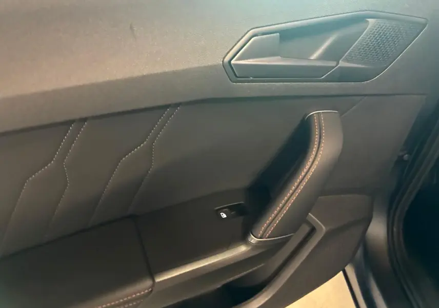Détail de la porte côté conducteur du CUPRA Formentor 1.4 E-HYBRID 2024 avec surpiqûres orange sur cuir noir.