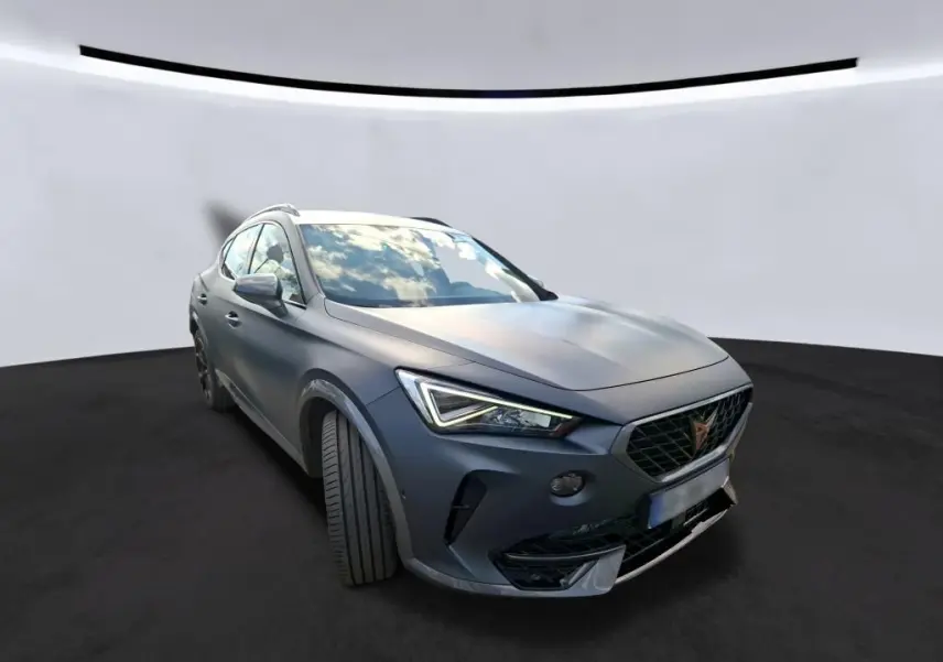 Vue 3/4 avant gauche d'une CUPRA Formentor 1.4 E-HYBRID 245 DSG6 VZ gris foncé mat avec jantes noires et cuivrées.