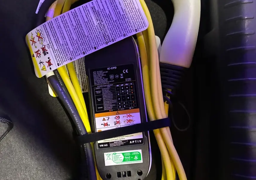 Câble de recharge jaune et noir pour CUPRA Formentor 1.4 E-HYBRID 245 DSG6 VZ, posé dans le coffre noir.