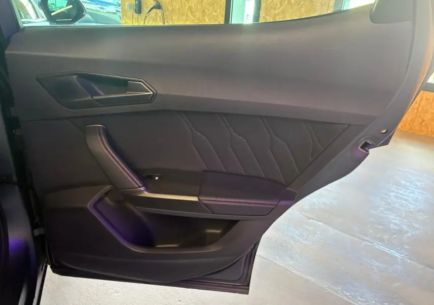 Vue intérieure côté gauche de la porte arrière d’une CUPRA Formentor gris foncé mat avec surpiqûres décoratives.