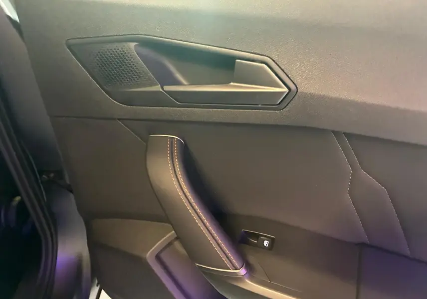Détail de la poignée de porte intérieure côté gauche du CUPRA Formentor 1.4 E-HYBRID 2024 en cuir noir avec surpiqûres.