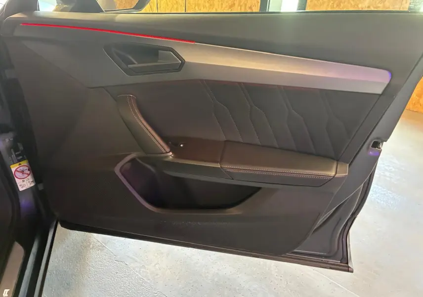 Vue rapprochée de la porte avant gauche intérieure noire avec surpiqûres contrastantes du CUPRA Formentor gris foncé mat 2024.