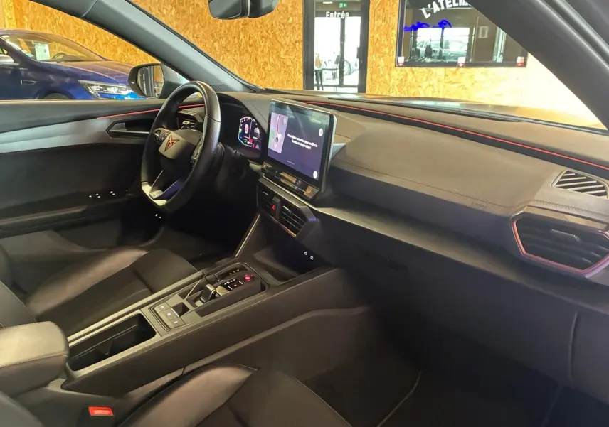 Vue intérieure côté conducteur de la CUPRA Formentor 1.4 E-HYBRID 2024 avec tableau de bord noir et écran tactile central.
