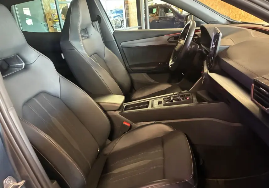 Vue intérieure côté conducteur du CUPRA Formentor 1.4 E-HYBRID 245 DSG6, sièges noirs et tableau de bord moderne.