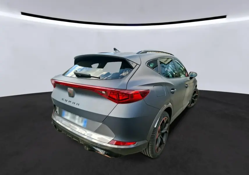 Vue 3/4 arrière droite du CUPRA Formentor gris foncé mat avec feux arrière allumés et jantes noires distinctives.