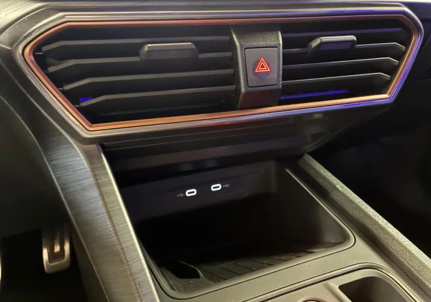 Gros plan sur la console centrale noire du CUPRA Formentor 1.4 E-HYBRID 2024 avec prises USB-C et bouton de warning.