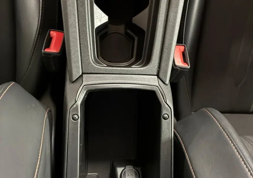 Vue plongeante sur la console centrale noire du CUPRA Formentor 1.4 E-HYBRID avec porte-gobelets et prise 12V visible.