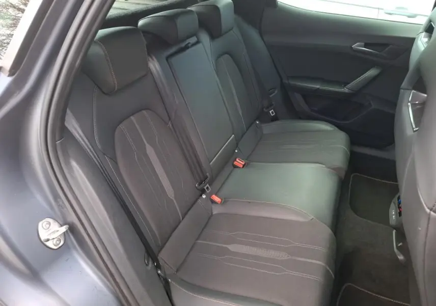 Vue 3/4 arrière droite d’un CUPRA Formentor 1.4 E-HYBRID gris foncé mat avec feux arrière allumés en intérieur.
